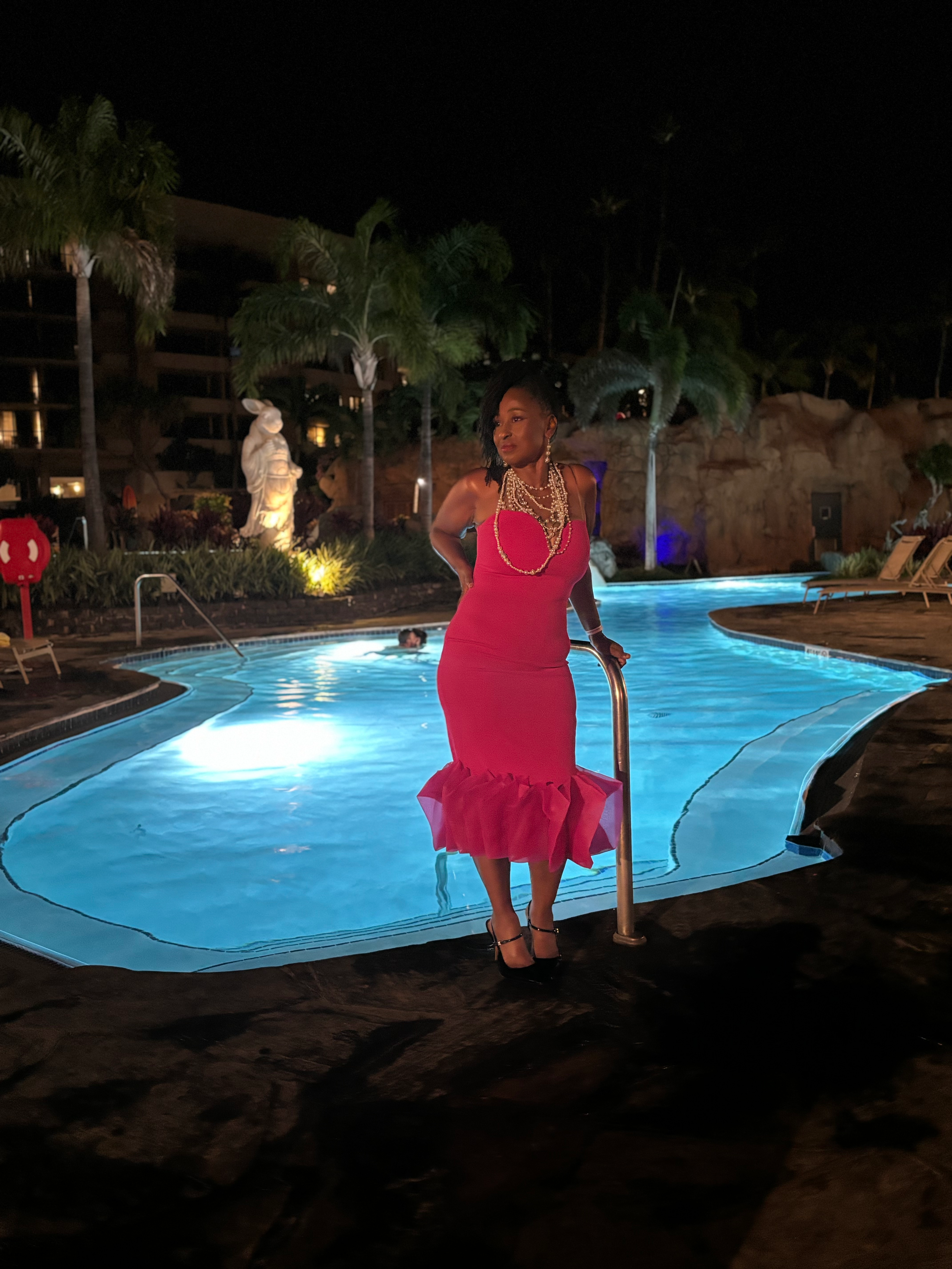 Tammy Smith in a pink dress by a glowing resort pool